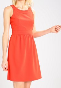 Červené bezramenné šaty s kulatým výstřihem, přiléhavým tělem a rozšířenou sukni. Vyrobené z hladkého materiálu s minimem švů.