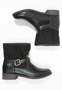Botas de tobillo negras con un upper de tela de crochet texturizada, acabados de cuero suave, una hebilla en tono dorado y un tacón bajo apilado.