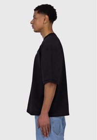 Schwarzes, übergroßes T-Shirt mit kurzen Ärmeln, aus weicher Baumwolle gefertigt. Hat ein einfaches Design mit einem runden Halsauschnitt und ohne sichtbare Muster.
