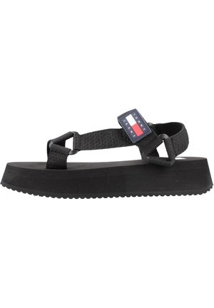 Schwarze Plattform-Sandalen mit strukturiertem Gummisohle, verstellbaren Stoffriemen und einem Markenlogo-Patch mit rot-weißen und blauen Akzenten.