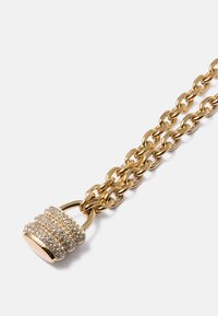 Colar de corrente de ouro com um pendente em forma de fechadura coberto com strass transparentes, apresentando uma superfície texturizada e um acabamento brilhante.