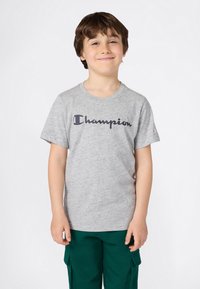 T-shirt in cotone grigio con maniche corte, caratterizzato dal logo "Champion" in blu scuro. Nessun motivo. Design con collo rotondo standard.