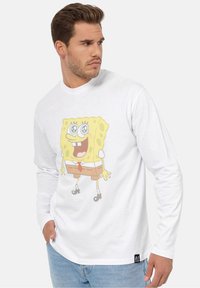 Hvid langærmet skjorte med et farverigt grafik af SpongeBob Firkant. Blødt stof med en afslappet pasform og rund halsudskæring.