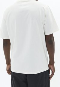 Weißes Baumwoll-T-Shirt mit Rundhalsausschnitt und kurzen Ärmeln, gerade geschnitten und mit weicher Textur. Keine Grafiken oder Muster sichtbar.