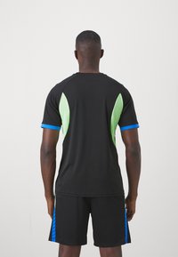 Svart atletisk tröja med gröna och blå accenter, korta ärmar och ett lätt material. Svarta shorts med blå sidosträck.