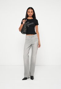 Czarny krótki t-shirt z logo "Guess", szare szerokie jeansy, czarna torebka i czarne czółenka na szpic. Gładkie tekstury na całej powierzchni.