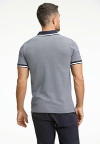 Polo grigia con tessuto testurizzato, caratterizzata da colletto blu navy e dettagli a strisce sulle maniche. Maniche corte e vestibilità aderente sono evidenti.