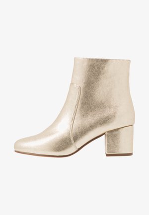 Gold metallic ankle boots with a pointed toe, smooth texture, and a block heel. Features a slip-on design with no visible hardware.