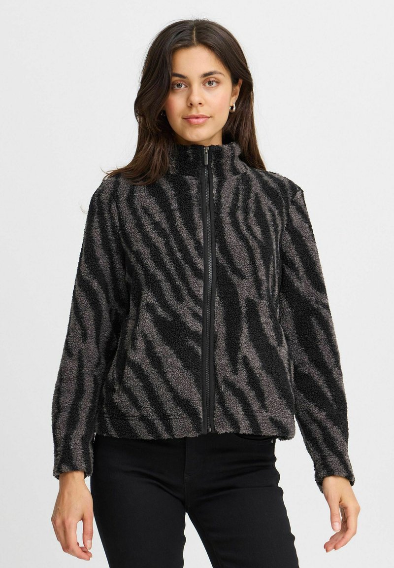 Veste en polaire noire et grise avec fermeture éclair devant, col montant et motif zébré. Présente une coupe décontractée et une surface texturée.