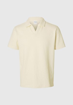 Koszulka polo z krótkim rękawem w jasnym żółtym, teksturowanym materiale, z dekoltem w serek i luźnym krojem, z subtelnym wzorem w romby.