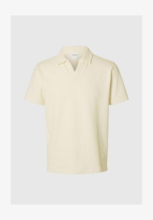 Kortermet polo-skjorte i lys gul teksturert stoff med V-hals og avslappet passform, med et subtilt diamantmønster.