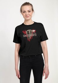 Camiseta de algodón negra con un estampado gráfico que presenta "SAN FRANSOKYO" en blanco y rojo, sobre un diseño de siluetas de paisajes urbanos.
