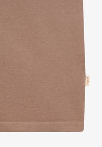 Gros plan sur un tissu tricoté marron avec une petite étiquette beige portant la mention "B. KID'S" cousue sur le bord droit.