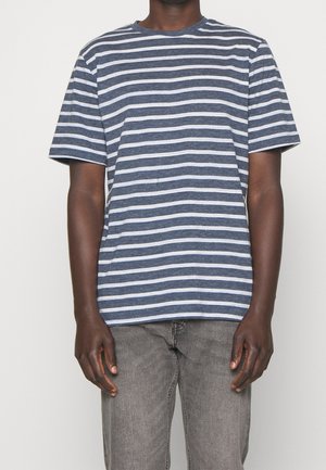 T-shirt à manches courtes rayé bleu et blanc, col rond, fabriqué en tissu doux. Associé à un jean gris. Détails de couture visibles.
