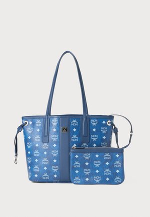 Μπλε τσάντα παραλίας με διπλές λαβές, με ανάγλυφα λογότυπα MCM και διαμαντένια σχέδια; περιλαμβάνει αποσπώμενη ταιριαστή θήκη. Λείο υλικό.