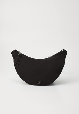 Black fabric bag in a crescent shape with a silver zipper and logo detail. Soft texture and minimalistic design.