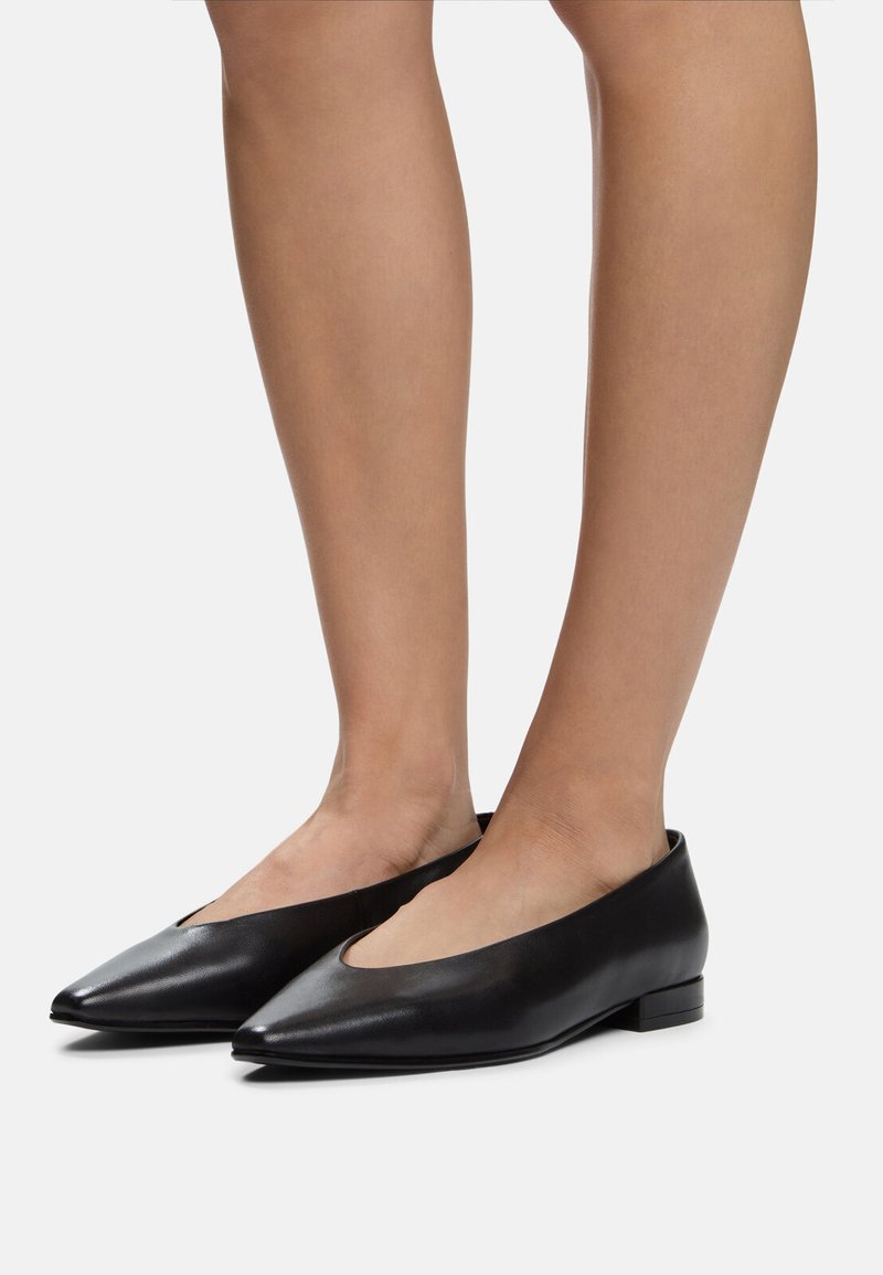 Ballerine in pelle nera con punta affusolata e tacco basso. Presentano un'apertura ampia e una texture liscia e lucida.
