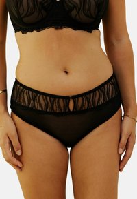 Culotte en dentelle noire avec un panneau supérieur transparent, des bords festonnés et une petite ouverture en clé à l'avant. Tissu doux avec une texture lisse.