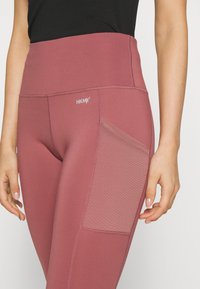 Snygga träningstights i en dämpad rosaton, med hög midja, sidoficka och slät elastisk material med förstärkta sömmar.