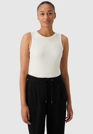 Witte geribbelde tanktop met een ronde halslijn, gecombineerd met zwarte jogpants met trekkoord. De outfit heeft een aansluitend ontwerp en een zachte textuur.