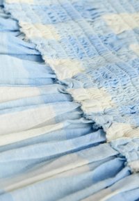 Gros plan sur un tissu bleu et blanc froncé avec un smock élastique et une texture froncée.