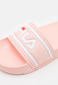 Infradito rosa con superficie in gomma testurizzata, dotate di una fascia bianca a righe e un logo in rilievo. Design slip-on per un facile indossamento.