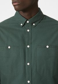 Groene button-up blouse van een gestructureerde stof, met een puntige kraag, witte knopen en twee borstzakken met rechte zoom.