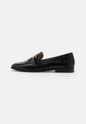 Zwarte leren loafer met krokodillenstructuur, gouden gespdetail, lage hak en puntige neus op witte achtergrond.