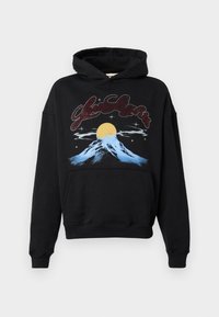 Svart huvtröja med en stor framsida grafisk design som visar ett stiliserat berg, en gul sol och en stjärnklar himmel. Materialet verkar mjukt och texturerat.