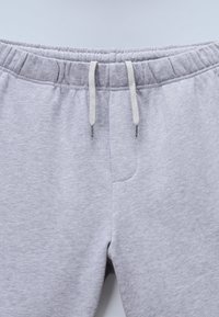 Γκρι φόρμες με ελαστική μέση, κορδόνι και πλαϊνή τσέπη· μαλακό βαμβακερό ύφασμα με λεία υφή.