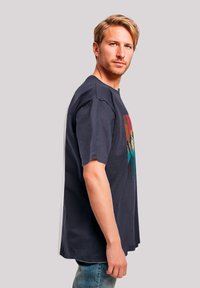 Marineblauwe t-shirt met korte mouwen en een kleurrijk grafisch ontwerp van bergen. Katoenen stof, ontspannen pasvorm met een rechte zoom.