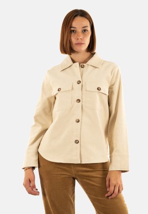 Veste chemise en velours côtelé crème avec col, fermeture à boutons et deux poches poitrine. Comprend des boutons marron clair et des manches longues.