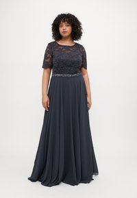 O rochie de seară de un albastru închis, cu un corset din dantelă, mâneci scurte și un talie decorată cu mărgele. Fusta vaporoasă este realizată dintr-un material ușor și moale.