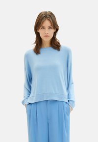 Lichtblauwe, oversized gebreide trui met een ronde hals, dolmanmouwen en een geribbelde zoom. Gepaard met bijpassende losse blauwe broek.