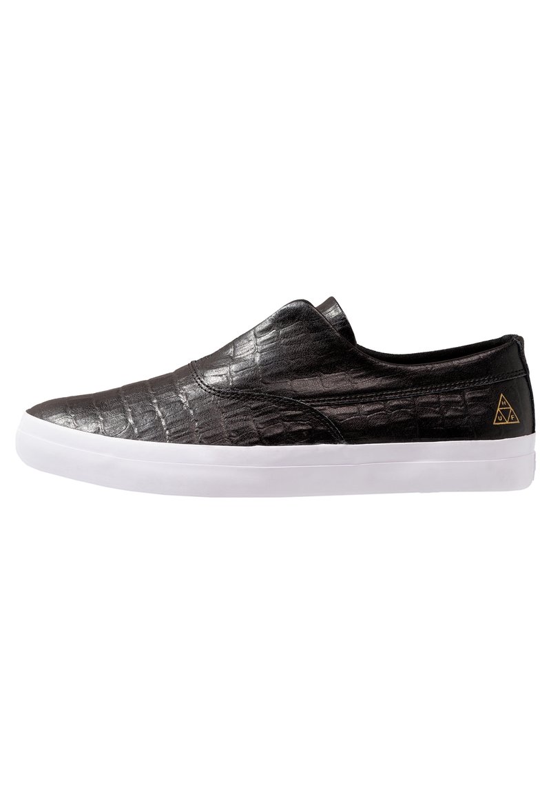 Baskets slip-on avec tige en cuir texture crocodile noir et semelle en caoutchouc blanche, présentant un petit logo triangulaire doré près du talon.