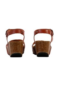 Sandalias de cuña de cuero marrón con correas ajustables en el tobillo y tacones de corcho. La suela es negra y tiene un agarre texturizado. Diseñadas para un uso casual.