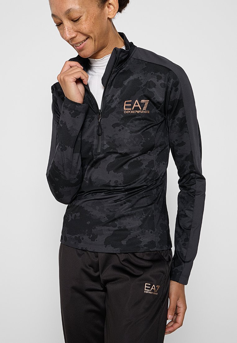 Černý sportovní zip-up top s maskáčovým vzorem a logem EA7. Hladká tkanina s přiléhavým střihem. Spárováno s volnými tmavými kalhotami.