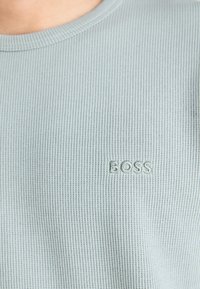 Lichtblauw geribd shirt met korte mouwen, gemaakt van zachte stof, met een geborduurd "BOSS" logo op de linkerborst.
