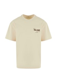 T-shirt en coton beige à coupe décontractée, avec un motif graphique brun sur le côté gauche de la poitrine, un col rond et des manches courtes.