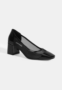 Schwarze High Heels mit glänzender Lackspitze und -absatz, transparenten Meshelementen an den Seiten und einem stabilen Blockabsatz.