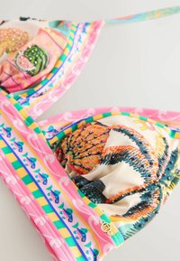 Colorful bikini top with embroidered floral and fruit patterns, pink, yellow, green striped trim, and a small gold charm on fabric edge.