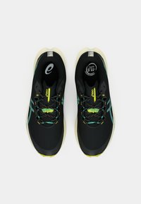 Sorte atletiske sko med en struktureret tekstiloverdel, der har akvafarvede accenter, reflekterende detaljer og gule snørebånd. Letvægts således design.