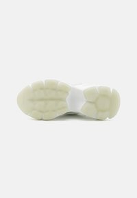 Witte sneakerzool met een textuur van rubber in een hoekig patroon, voorzien van een doorzichtige tussenzool en duidelijke gripnoppen voor grip.