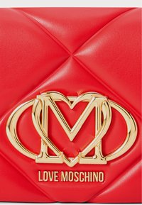 Borsa a tracolla in ecopelle trapuntata rossa con un logo dorato Love Moschino e design a cuore intrecciato, accompagnata da evidenti dettagli di cucitura.