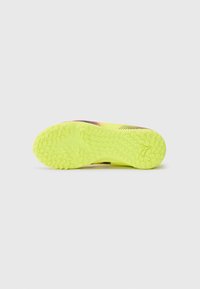 Semelle de chaussure de sport jaune vif avec un caoutchouc texturé pour l'adhérence. Présente des motifs circulaires et un logo au centre.