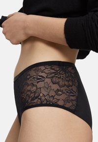 Sorte trusser med en blomstret blondepanel, blød linning og glat stof. Designet fremhæver indviklede blonde detaljer mod en ensfarvet baggrund.