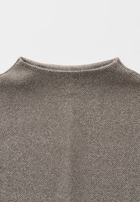 Nahaufnahme eines braunen und grauen strukturierten Stoffpullovers mit Rundhalsausschnitt vor einem einfarbigen weißen Hintergrund.