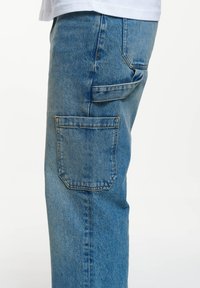 Jeans de mezclilla azul claro con corte recto, que presentan un bolsillo cuadrado en el lateral y costuras reforzadas a lo largo de las costuras.