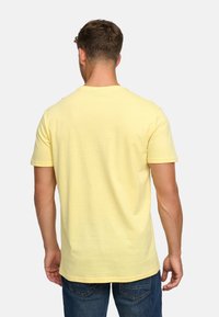 T-shirt en coton jaune clair à manches courtes et col rond, avec une texture lisse et un ourlet droit en bas.