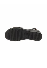 Sole di sandalo nera con una superficie in gomma texturizzata, caratterizzata da multiple scanalature per una maggiore trazione e un piccolo logo vicino al tallone.